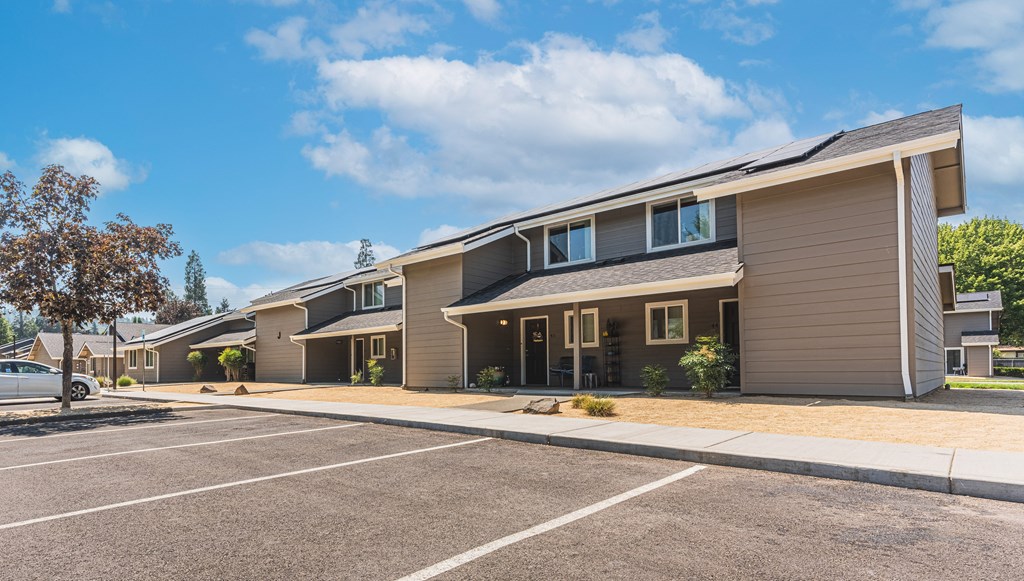 a row of houses with a parking lot and a blue sky