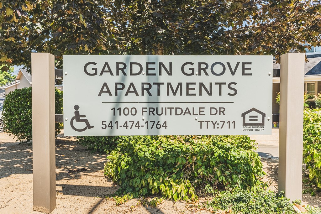 a garden grove apartments sign in front of a tree
