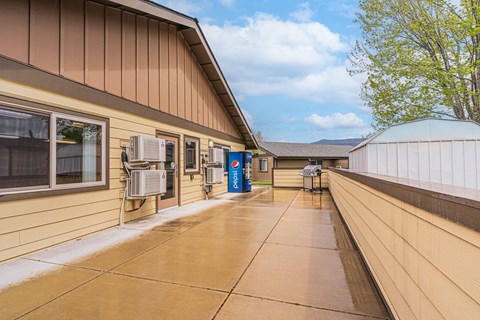 the entrance to a building with a patio and air conditioning units on the side