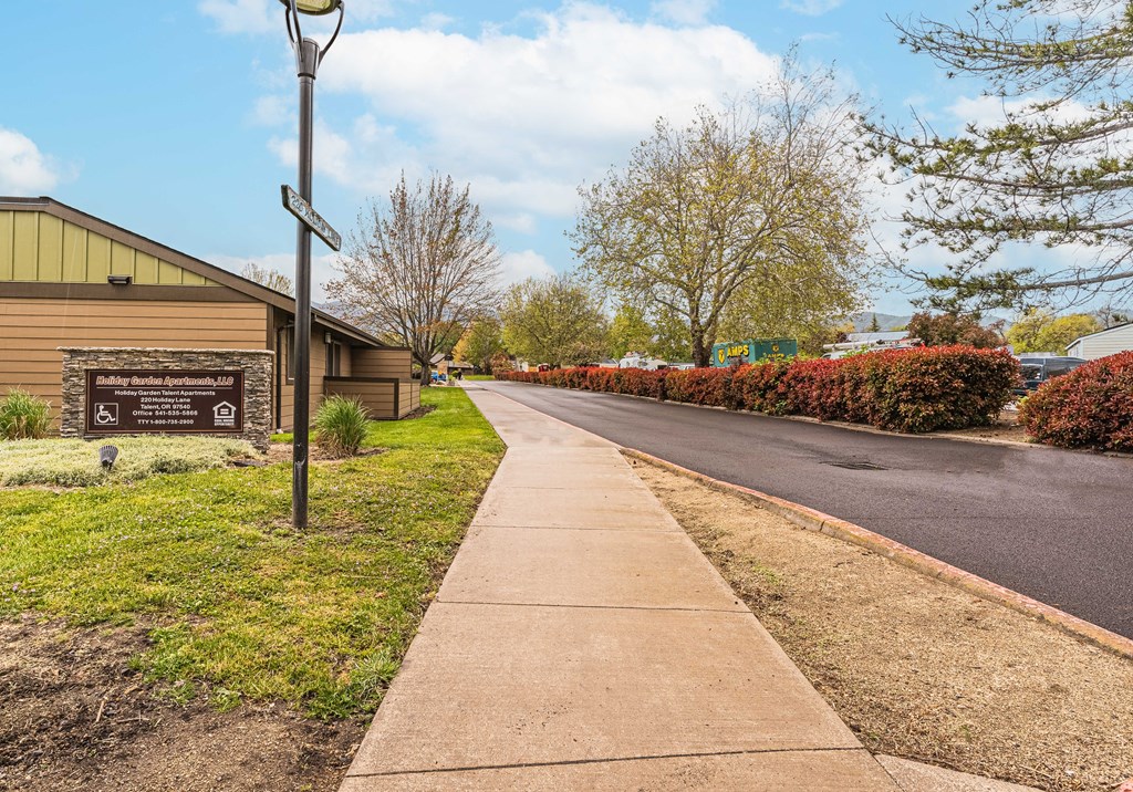 a sidewalk in front of a building with a sign on the side of the road