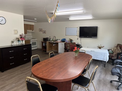 a dining room with a table and a kitchen with a tv