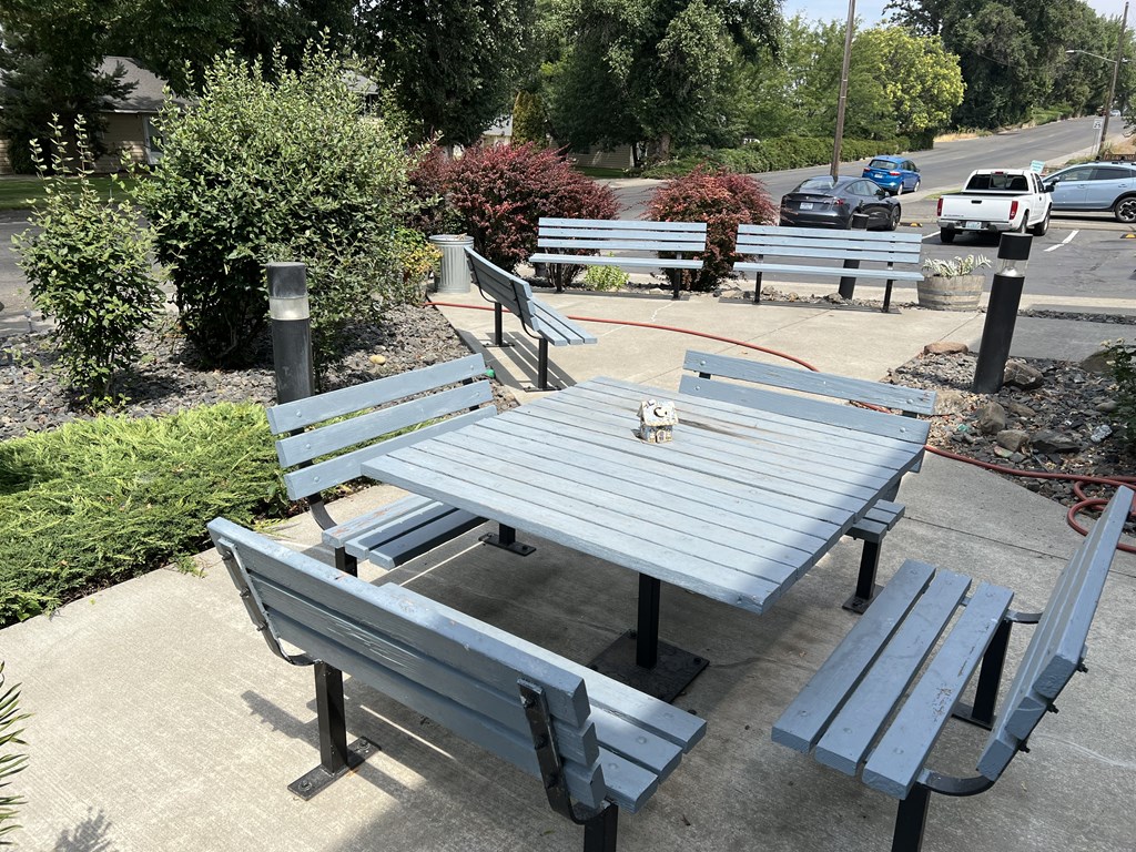 a picnic table and benches on a sidewalk
