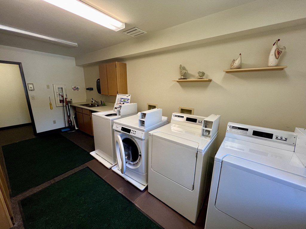 an image of a laundry room with four washers and dryers and a sink