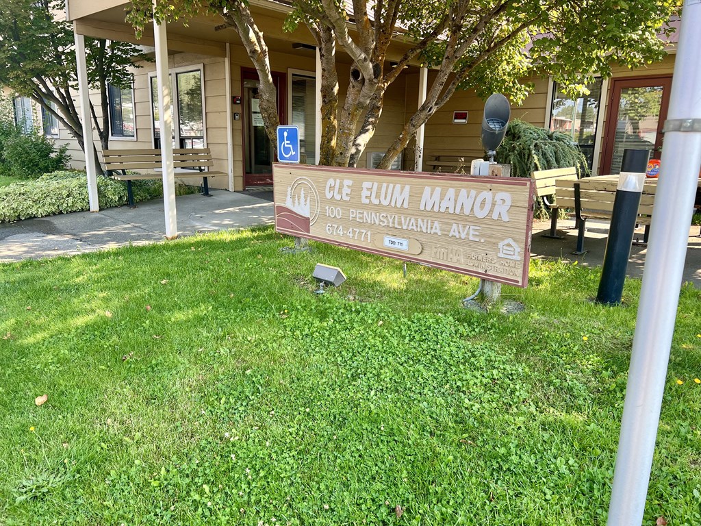 a sign in the grass in front of a building