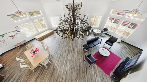 A dining room with a chandelier, a table with chairs, and pictures on the wall.