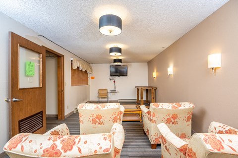 A room with a sofa, chairs and a television.