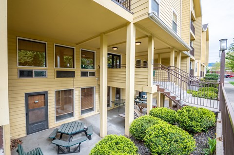 A yellow building with a balcony and a table and chairs on the patio.