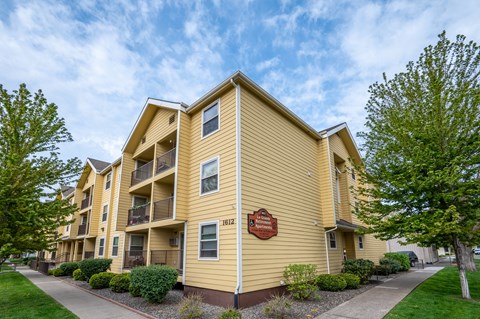 A yellow apartment building with a red sign on the front.