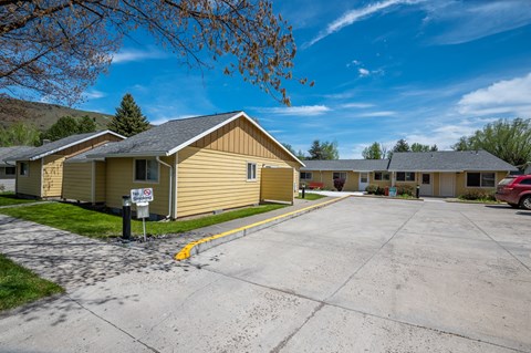 an empty parking lot in front of a yellow house