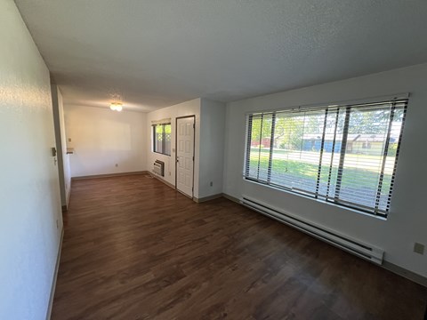 A room with wooden floors and a window with blinds.