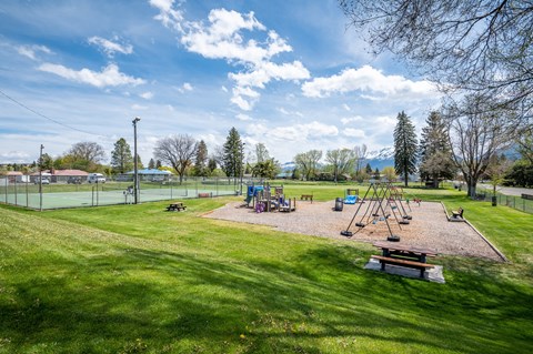 a playground with swings and a picnic table in a park