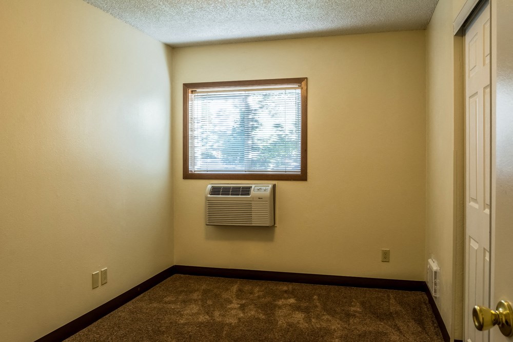 an empty room with a window and a air conditioner