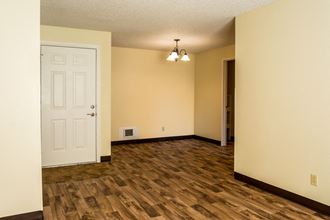 an empty living room with a white door and wood flooring