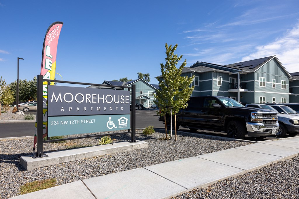 a sign for moorestown apartments with a truck parked in front of a building
