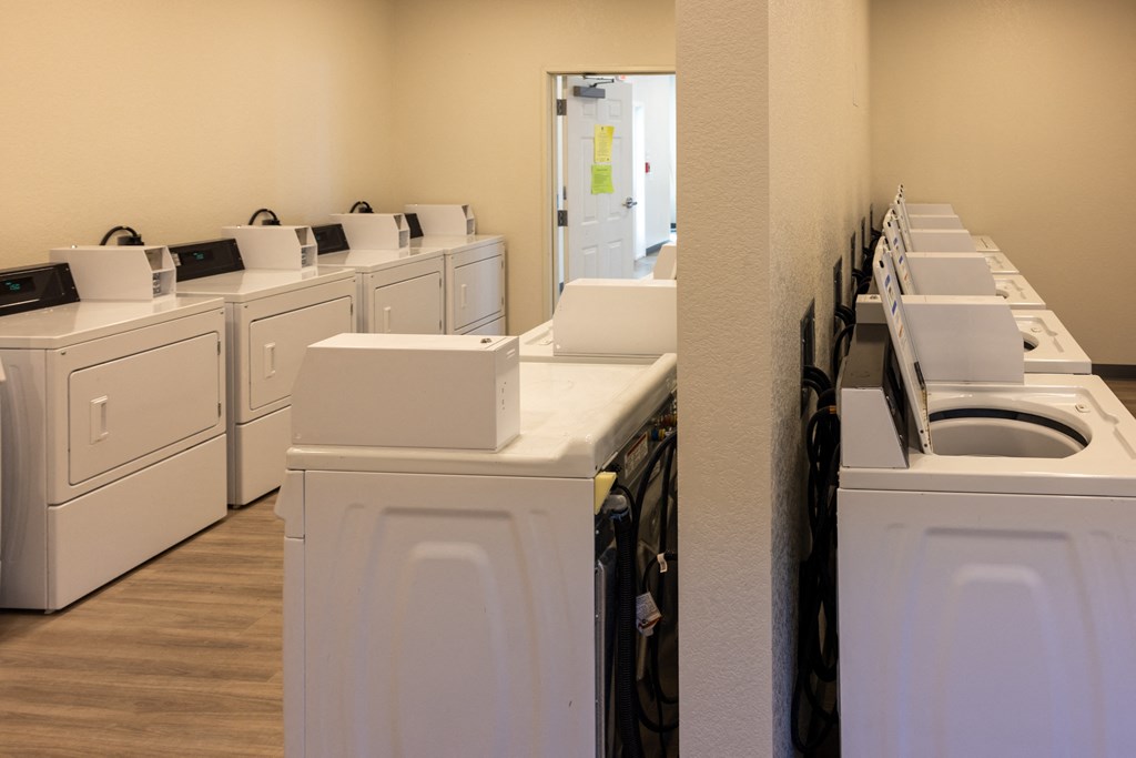 a row of washers and dryers in a laundromat with white machines
