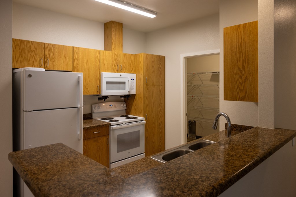 a kitchen with a granite counter top and a stove and refrigerator