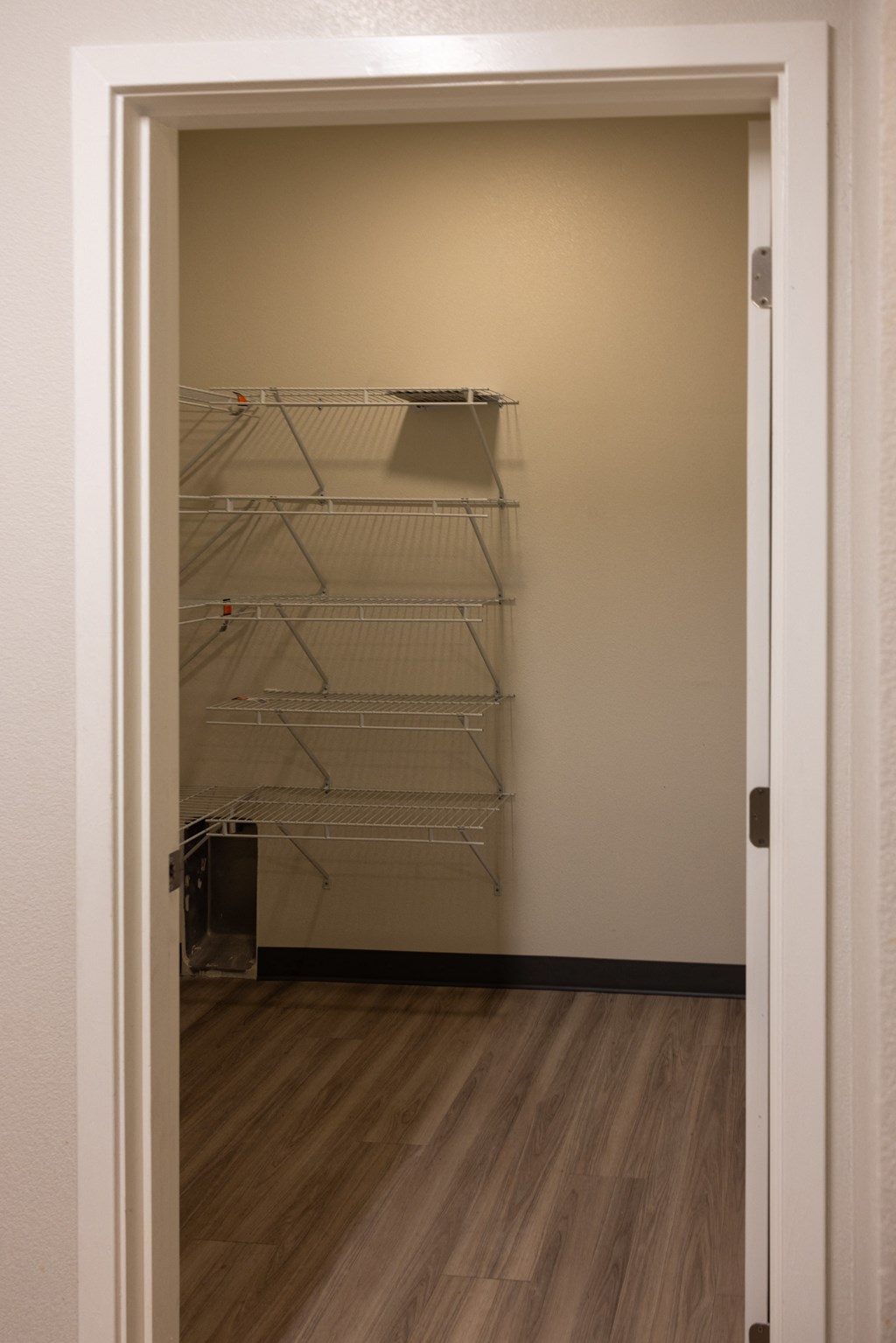 a room with a white door and a mirrored closet with shelves