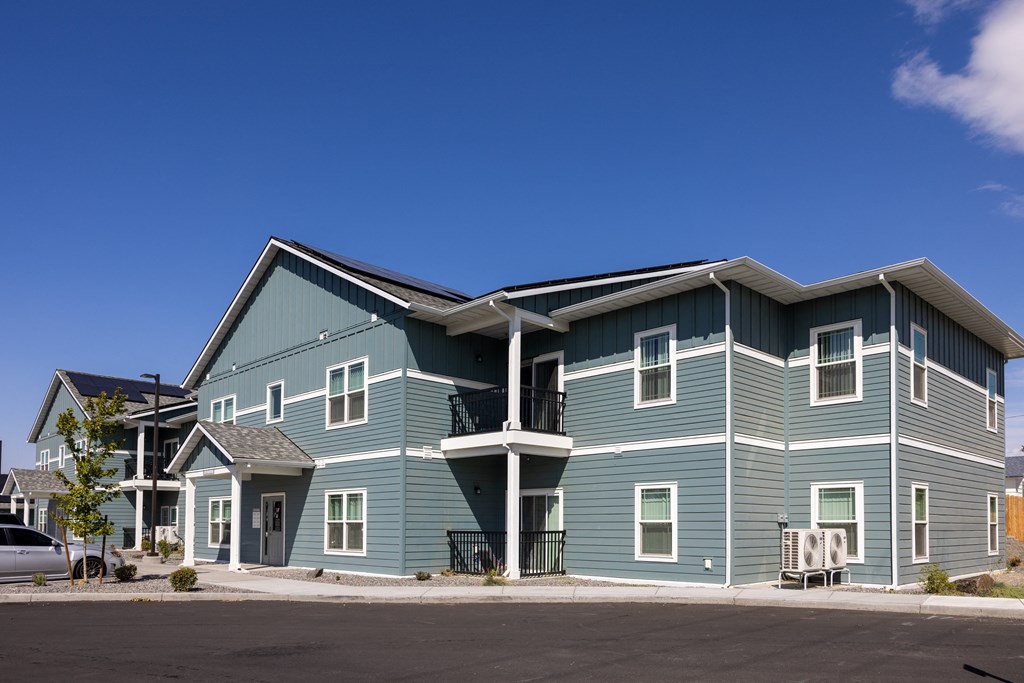 a large blue house with a street in front of it
