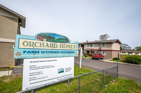a sign that reads orchard homes farm worker housing with a building in the background
