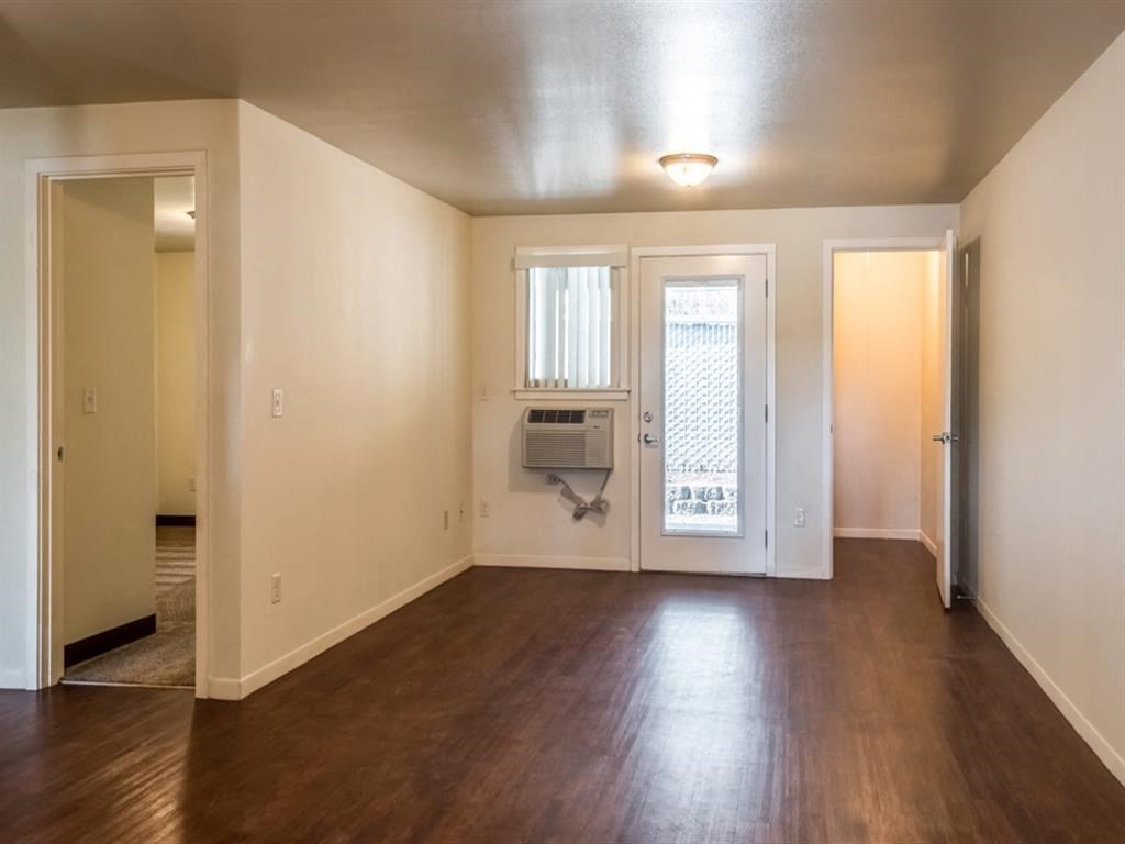 an empty living room with a hard wood floor and a window