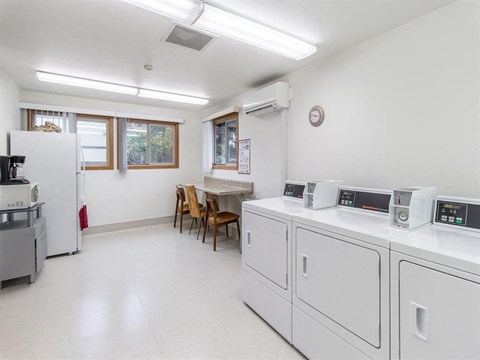 a laundry room with washes and dryers and a table with chairs