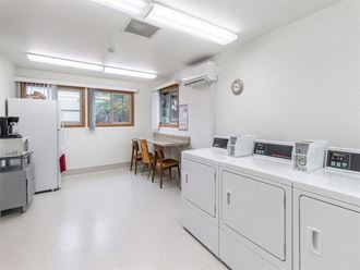 a laundry room with washes and dryers and a table with chairs