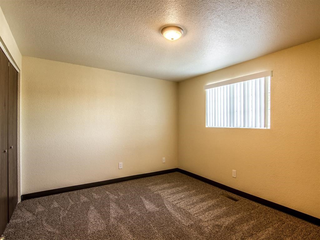 an empty living room with a window and carpet