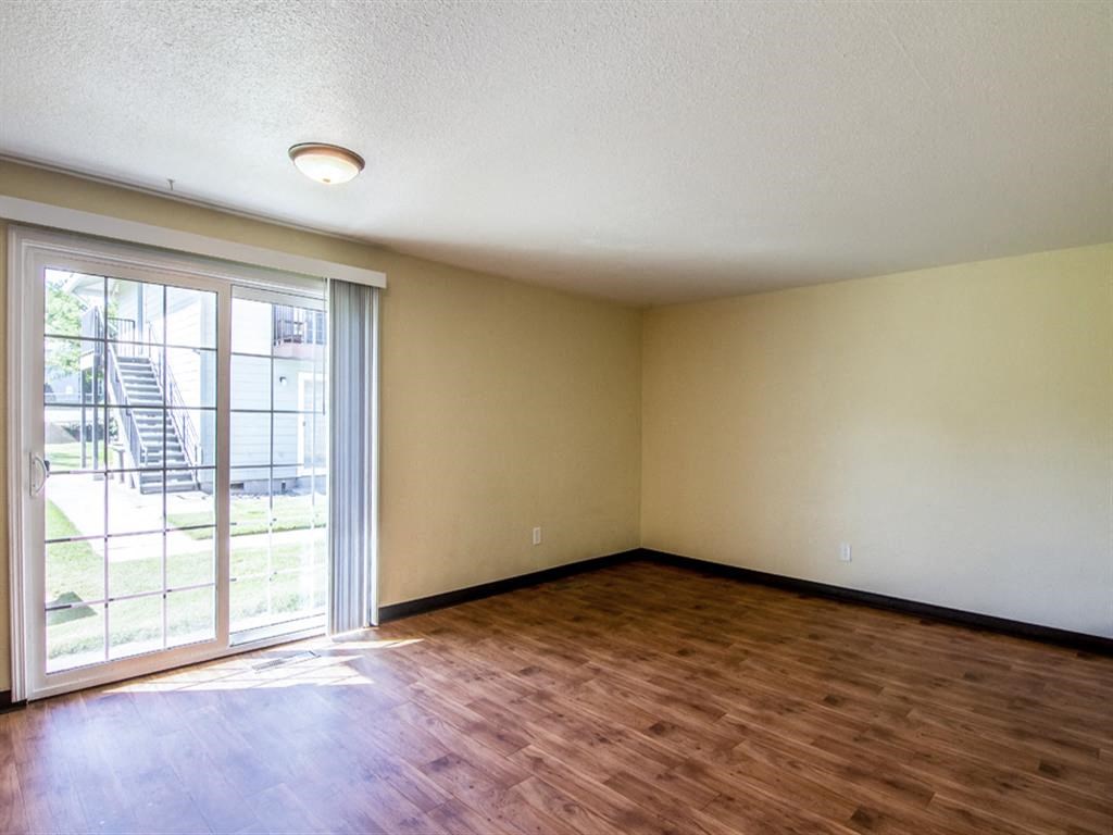 an empty living room with wood flooring and a sliding glass door