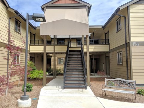 a staircase leading up to an apartment building with a bench