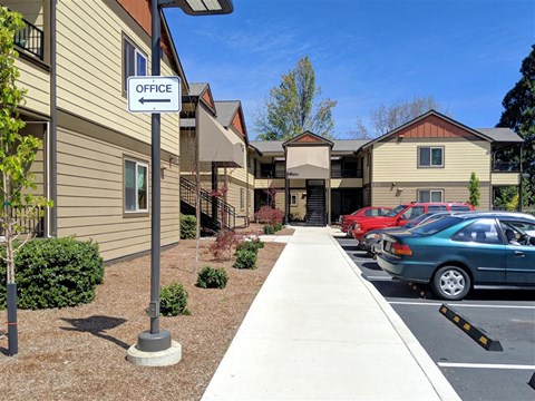 a sidewalk in front of an office building with cars parked
