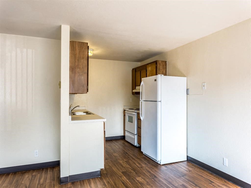 an empty kitchen with a refrigerator and a stove