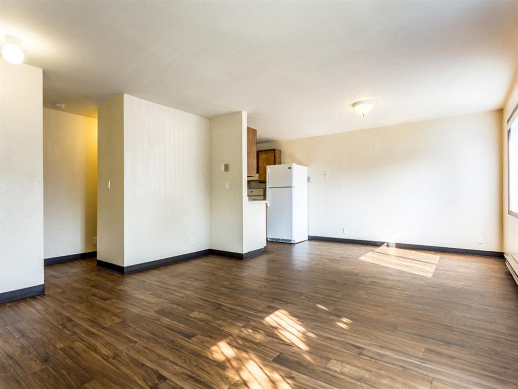 an empty living room with a refrigerator and