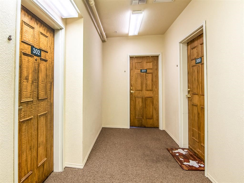 a hallway with two wooden doors and a carpeted floor
