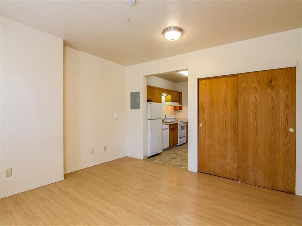 an empty living room and kitchen with a wood floor