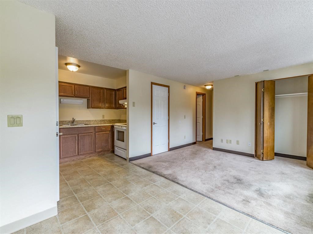 an empty living room and kitchen with the door open