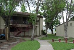a house with trees and a sidewalk in front of it