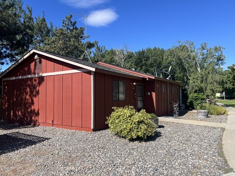 A red building with a gravel driveway in front.