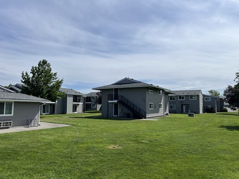 A grassy field with a few houses in the background.