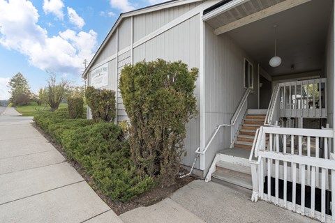 A white building with a porch and a sign on the side.