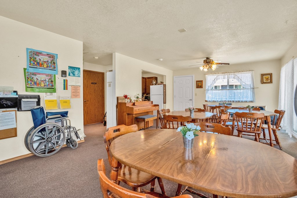a dining room with tables and chairs and a kitchen with a wheelchair