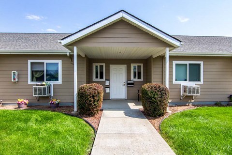 a small brown house with a sidewalk in front of it
