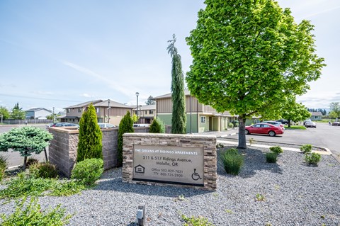 The sign in front of the building says "The Greens at Spring Apartments".