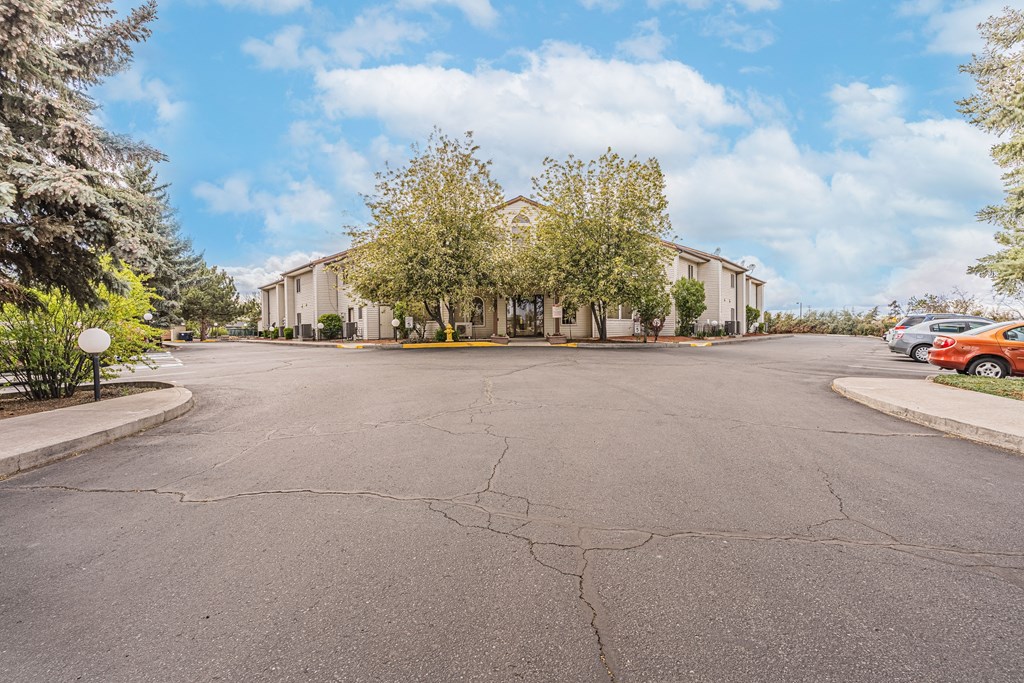 an empty street in front of a building with trees