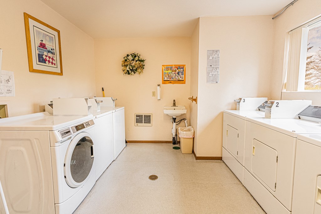 a washer and dryer in a laundry room with a sink and a window