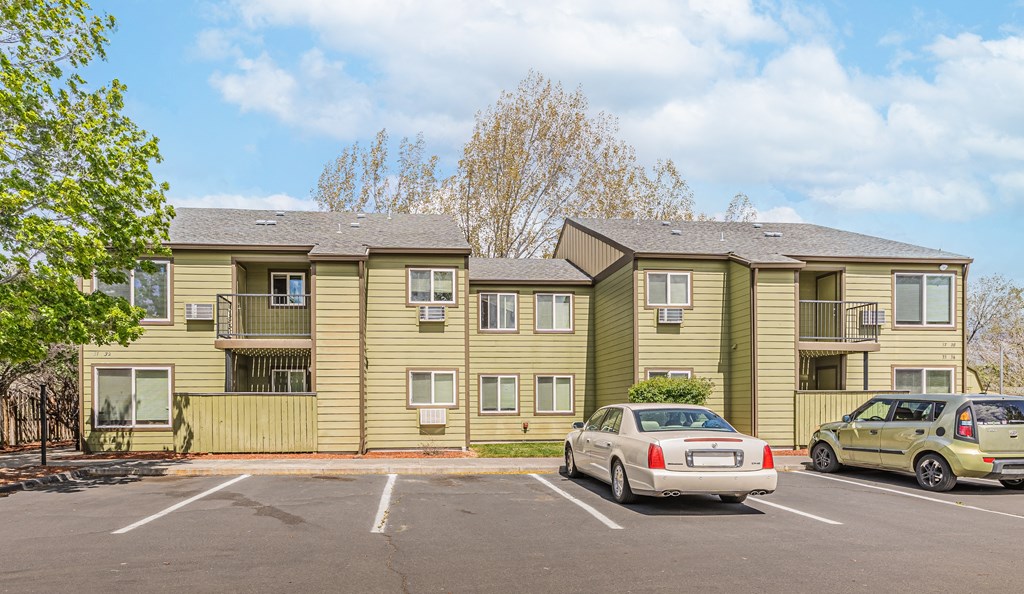 an apartment building with cars parked in a parking lot