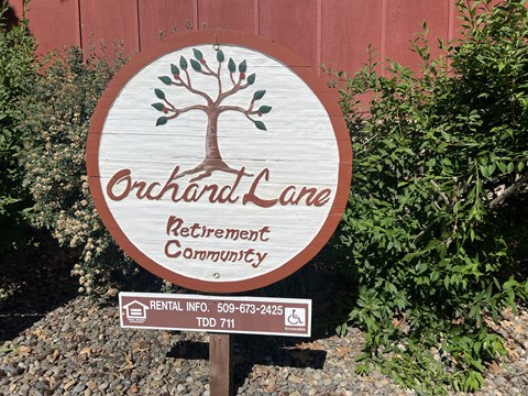 A sign for Orchard Lane Retirement Community with a tree symbol on it.