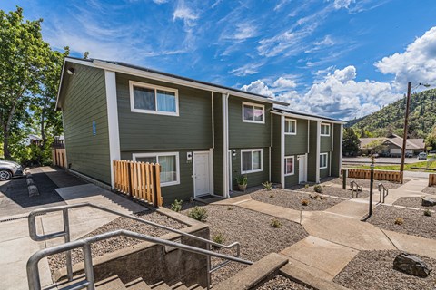 a green building with stairs and a yard in front of it