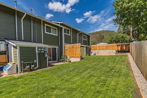 the backyard of a green house with a yard and a fence