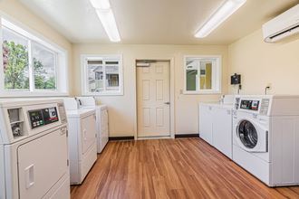 an empty laundry room with washes and dryers and a door to a room