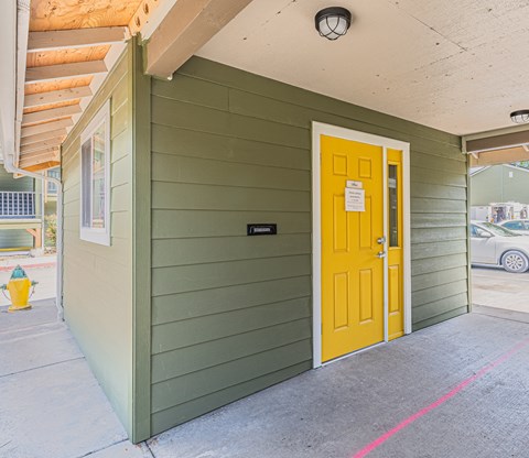 the front door of a green building with a yellow door